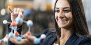 Eine junge Frau betrachtet ein naturwissenschaftliches Modell in ihren Händen.